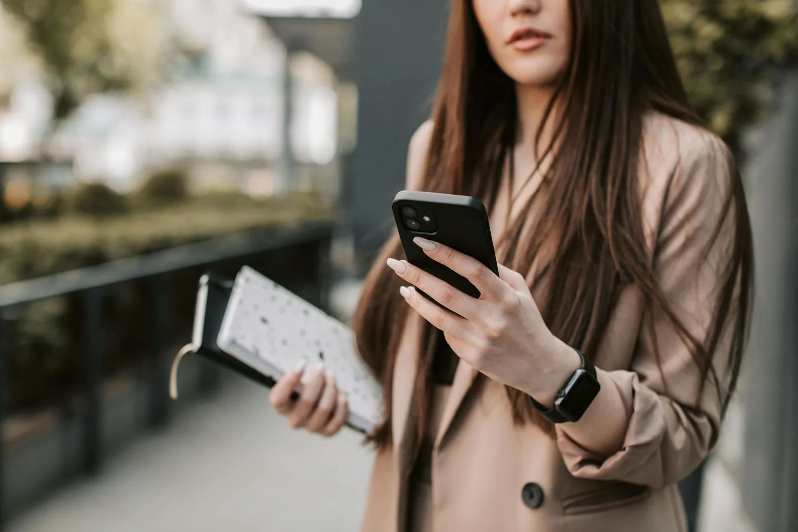 A professional holding a phone and notebooks